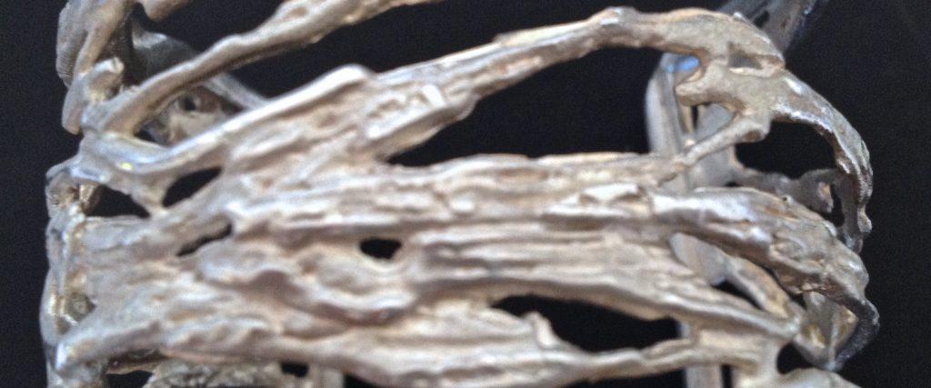 Cette présence est soulignée par leur volume, puisque ces 2 manchettes couvrent presque la moitié de l'avant bras et par le travail du métal, de l'or froissé, dans un esprit gréco antique, ou de l'argent comme de fines algues striées qui glissent sur le poignet.